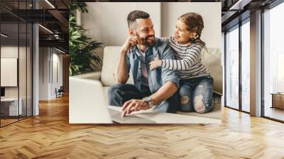 happy family a businessman father working at a computer and his child daughter  at home. Wall mural