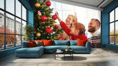 happy family mother, father and child daughter decorate Christmas tree  . Wall mural