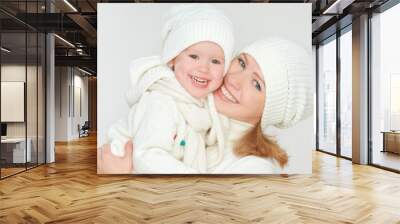 happy family: mother and baby daughter in white winter hats Wall mural