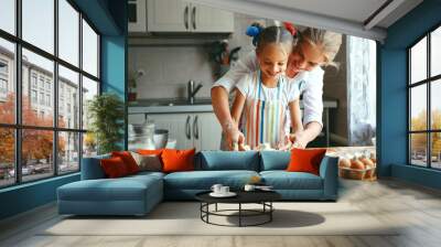 Happy family mother and daughter bake kneading dough in kitchen Wall mural