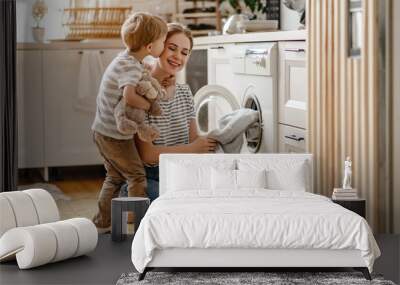 Happy family mother housewife and child   in laundry with washing machine . Wall mural