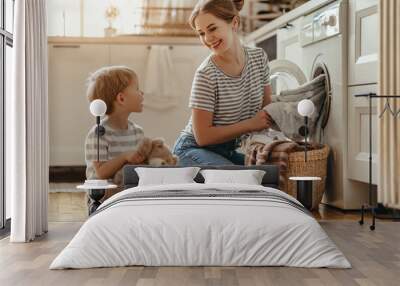 Happy family mother housewife and child   in laundry with washing machine . Wall mural