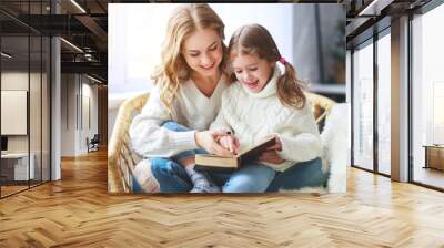 happy family mother reads book to child to daughter by window . Wall mural