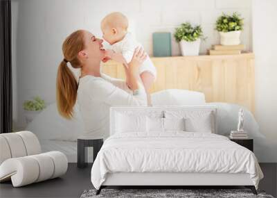 happy family mother  with baby playing and hug in bed Wall mural