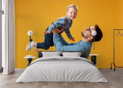 happy father's day! cute dad and son hugging on yellow background Wall mural