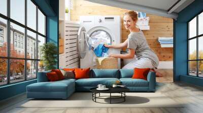 Happy housewife woman in laundry room with washing machine  . Wall mural