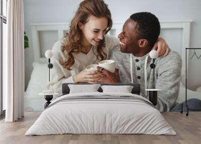 happy loving couple drinking cocoa on winter morning in bed Wall mural