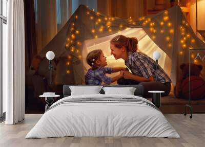 happy mother and daughter playing at home in tent . Wall mural