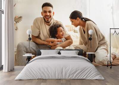 happy multi ethnic family mom, dad and child  laughing, playing and tickles   in bed   at home. Wall mural