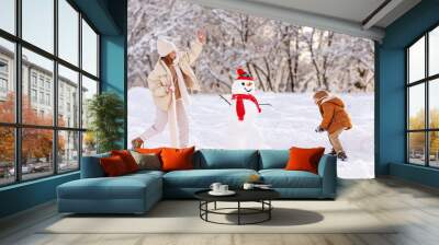 Happy overjoyed family mother and little son play snowballs outdoors in wintertime Wall mural