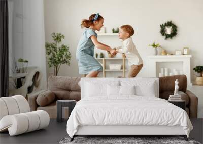 Happy siblings jumping on sofa. Wall mural