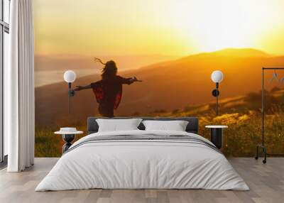 Happy woman  dances,  rejoices, laughs  on sunset in nature . Wall mural