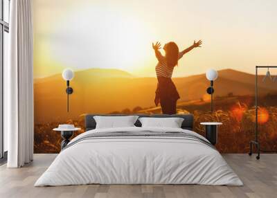 Happy woman jumping and enjoying life  at sunset in mountains. Wall mural