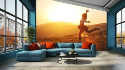 Happy woman jumping and enjoying life  at sunset in mountains. Wall mural