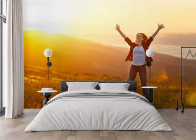 Happy woman   on sunset in nature iwith open hands Wall mural