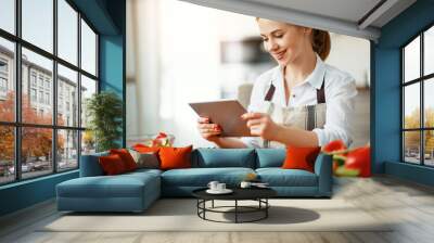 happy woman preparing vegetables in kitchen on prescription with tablet Wall mural