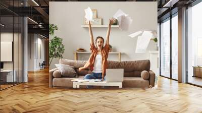 Happy young woman freelancer throwing papers. Wall mural