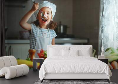 healthy eating. happy child girl prepares vegetable salad in kitchen Wall mural