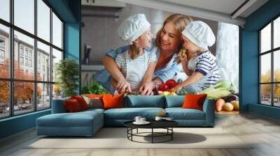 Healthy eating. Happy family mother and children  prepares   vegetable salad in kitchen. Wall mural