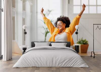 Joyful   business woman freelancer  entrepreneur smiling and rejoices in victory while sitting at desk   and working at laptop   after finishing project  in home office Wall mural