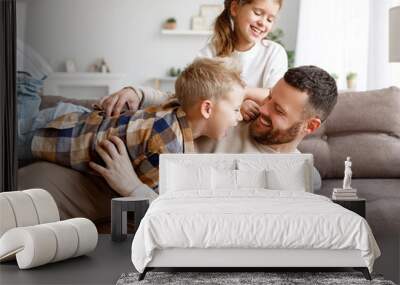 Kids playing with father on sofa Wall mural