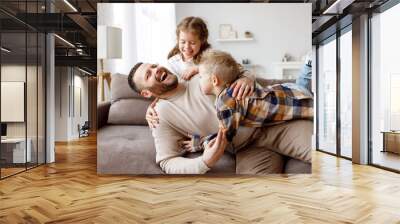 Kids playing with father on sofa Wall mural