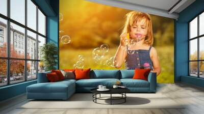 little girl blowing soap bubbles in nature Wall mural