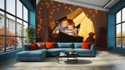 mother and child daughter with a book and a flashlight before going to bed Wall mural