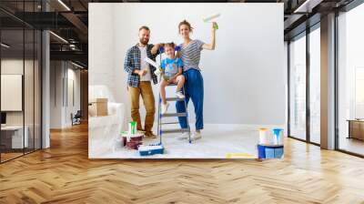 Repair in apartment. Happy family mother, father and child daughter  paints wall Wall mural