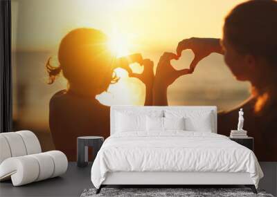 The concept of love, parenthood and happy family. Mother and child daughter show heart from hands at sunset Wall mural