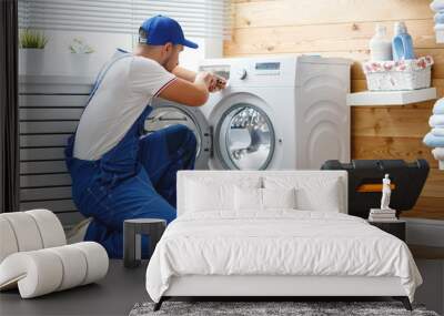 working man   plumber repairs  washing machine in   laundry. Wall mural