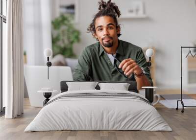 Young african american man freelancer working remotely on laptop or studying online at home Wall mural