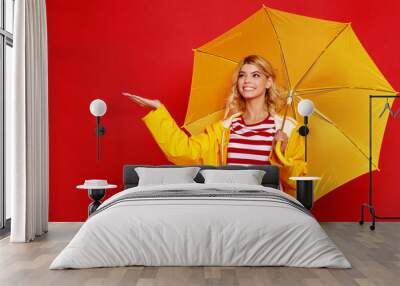 young happy emotional cheerful girl laughing and jumping with yellow umbrella   on colored red background. Wall mural