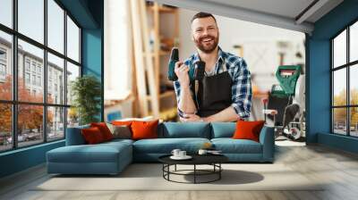 young male carpenter with screwdriver working in  workshop. Wall mural