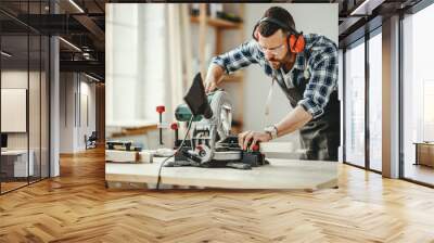 young male carpenter working in  workshop. Wall mural