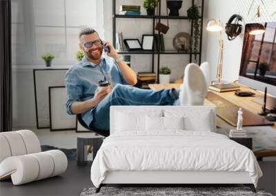 Young man is talking on the phone   at workplace. Wall mural