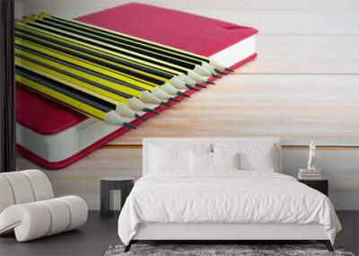 Wooden 2b pencils lying on red note book on wooden table. Copy space. Wall mural