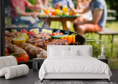 A barbecue grill loaded with various foods, such as vegetables and meats, with a group of friends in the background enjoying a party outdoors Wall mural