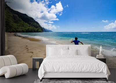 10 year old boy running on sunny day over golden sand at Ke'e Beach, Kauai, Hawaii Wall mural