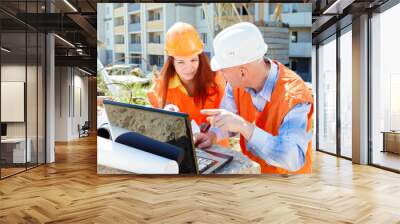 female and male construction workers looking at laptop and smili Wall mural