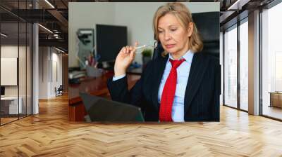 Portrait of mature female boss working in office sitting in a chair. Wall mural