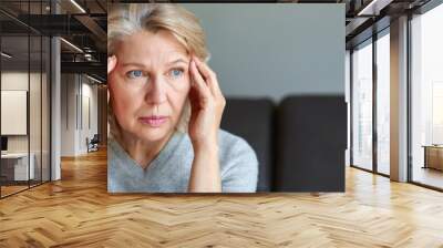 Woman suffering from a headache and stress holding her hands to her temples Wall mural