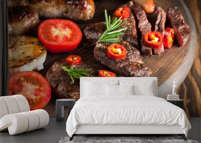 Close-up photo of mixed grilled meat platter. Beef, pork, poultry, sausages, grilled garlic, chili pepper, red tomatoes on wooden rustic background. Wall mural