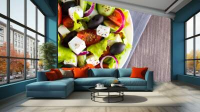 Fresh Greek salad made of cherry tomato, ruccola, arugula, feta, olives, cucumbers, onion and spices. Caesar salad in a white bowl on wooden background. Healthy organic diet food concept. Wall mural