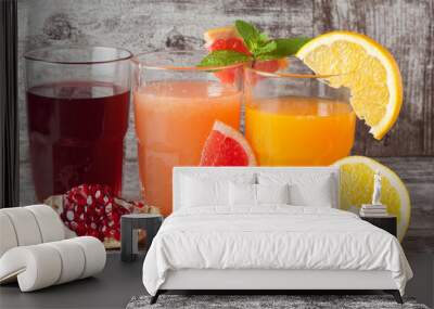 Glasses of pomegranate, grapefruit, orange juice on wooden background. Refreshments and summer drinks. Wall mural