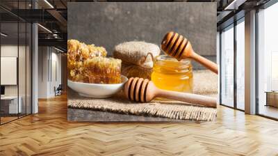 Honey dripping from a wooden honey dipper in a jar on wooden grey rustic background Wall mural