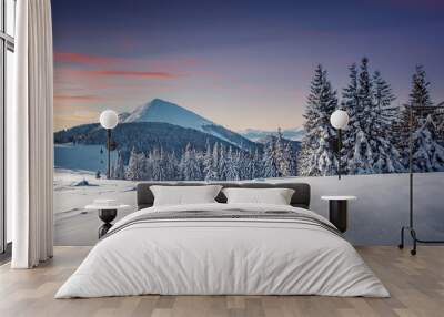 Fantastic winter sunset in the mountain. Panoramic view of the picturesque snowy winter landscape. Snow covered fir trees on the background of mountain peak. Christmas holiday concept Wall mural