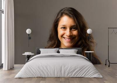 young mixed race woman wearing a black t shirt and jeans stands in full face view while smiling at v Wall mural