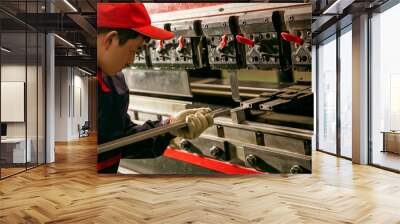 Asian worker using grinder to make heavy machine on assembly line Wall mural