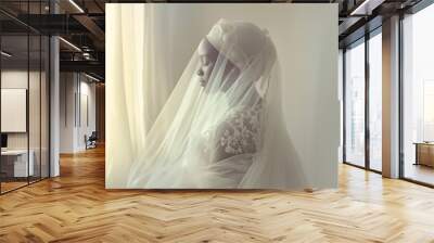 African bride wearing a white wedding dress facing a window in the morning light Wall mural